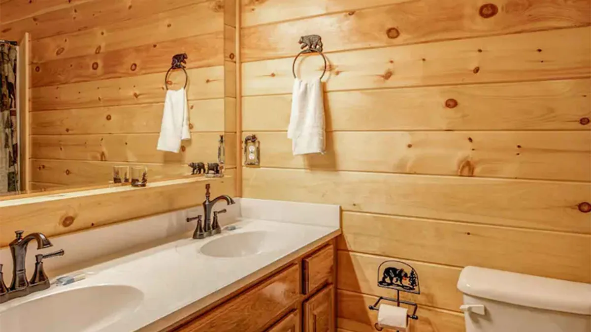 A spacious bathroom featuring a double sink vanity with wooden cabinetry, a large mirror, and bear-themed accessories. The space feels serene, well-lit, and exceptionally clean—ideal for morning routines or unwinding after a long day.