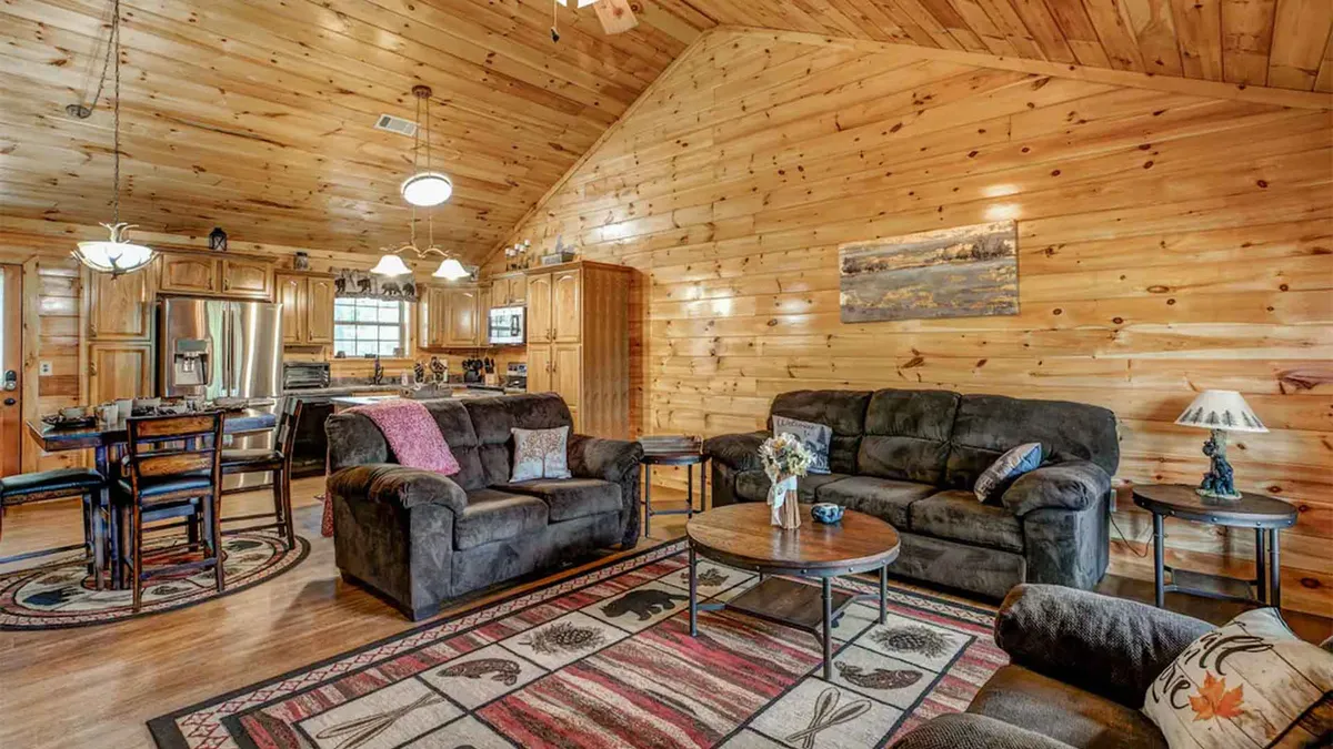 A comfortable, inviting scene showing a plush sofa set, a wooden dining table, a cozy rug, and wooden walls—all bathed in soft, natural light. This setting is ideal for relaxing, sharing stories, or enjoying a family game night.